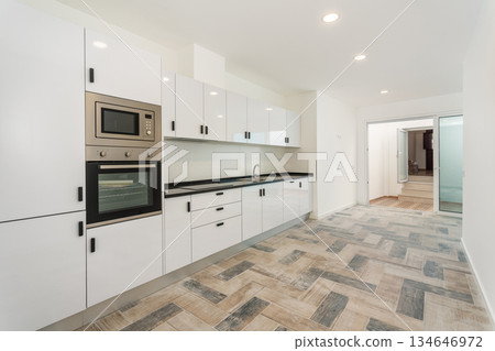 A bright and airy kitchen features white cabinets, a black countertop, and modern appliances, creating an inviting space for cooking and gatherings A bright and airy kitchen features white cabinets, a black countertop, and modern appliances, creating an inviting space for cooking and gatherings 134646972