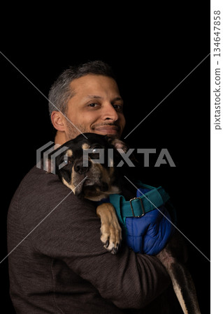 A man is holding a dog in his arms A man is holding a dog in his arms 134647858