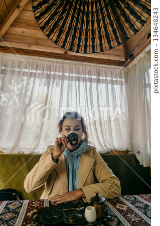 Woman Sipping Coffee in a Cozy Cabin Setting 134648243