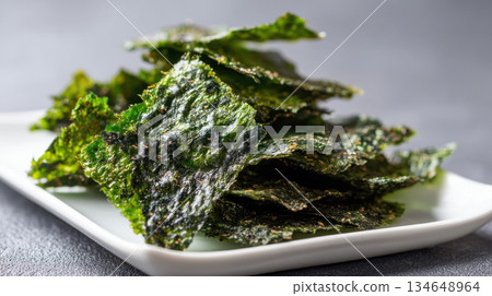 Crispy fried seaweed on a white plate, healthy Asian nori chips, and a light, savory snack 134648964