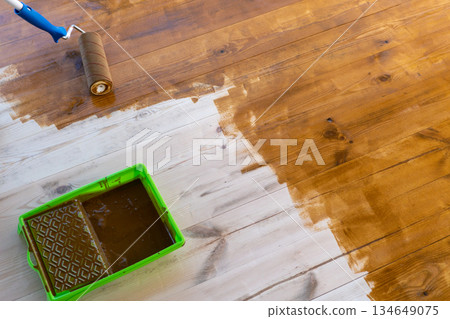 Wooden floor staining with paint roller and tray for home renovation project Wooden floor staining with paint roller and tray for home renovation project 134649075