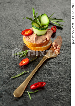 Bread slices with pate, cucumber, red pepper, and rosemary. Bread slices with pate, cucumber, red pepper, and rosemary. 134649280