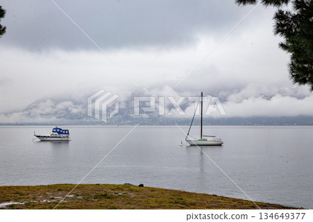 Sailoat and motooat (sheltering) next to coastline on Swiss Lake . Foggy. Sailoat and motooat (sheltering) next to coastline on Swiss Lake . Foggy. 134649377