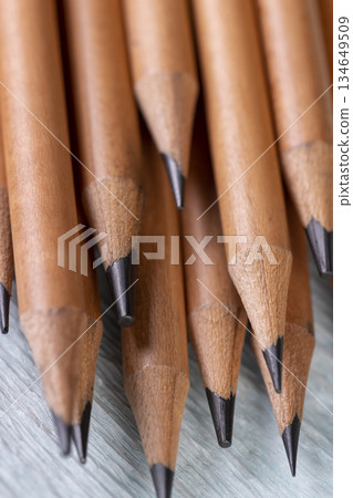 wooden pencils with black lead on blue corrugated paper, several pencils for sketches or graphic work are in a row. wooden pencils with black lead on blue corrugated paper, several pencils for sketches or graphic work are in a row. 134649509