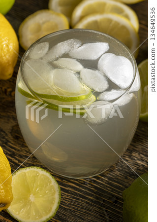cold lemon drink with the addition of pieces of pure ice in a glass, sweet and sour refreshing drink with lemon flavor and whole juicy limes 134649536