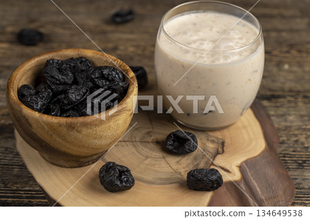creamy milk yogurt with black soft dehydrated fruits of black plum, delicious yogurt with flavor and pieces of prunes poured in a glass creamy milk yogurt with black soft dehydrated fruits of black plum, delicious yogurt with flavor and pieces of prunes poured in a glass 134649538