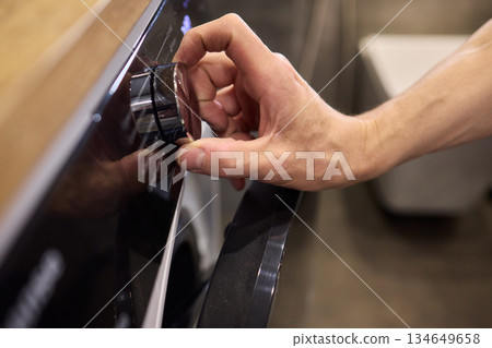 Individual Interacting with a Modern Washing Machines Control Panel for Efficient Laundry Tasks 134649658