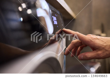 Individual Interacting with a Modern Washing Machines Control Panel for Efficient Laundry Tasks Individual Interacting with a Modern Washing Machines Control Panel for Efficient Laundry Tasks 134649663