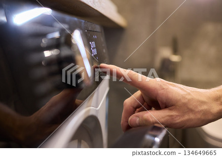 Individual Interacting with a Modern Washing Machines Control Panel for Efficient Laundry Tasks 134649665