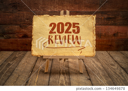 2025 year review - easel sign with antique paper against rustic wood, end of year business concept 134649878