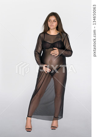 Beautiful stylish delicate pregnant woman in a black long transparent dress 134650063