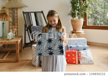 A girl unwraps the christmas presents A girl unwraps the christmas presents 134650152