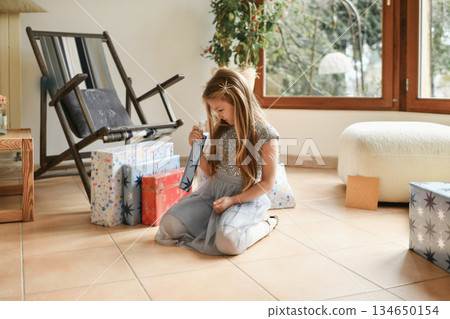 A girl unwraps the christmas presents A girl unwraps the christmas presents 134650154