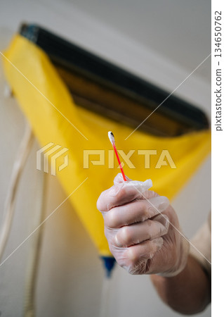 Closeup vertical cropped shot of technician in gloves cleaning mold from dirty air conditioner with cotton swab, promoting proper hygiene and ensuring maintenance for improved indoor air quality. Closeup vertical cropped shot of technician in gloves cleaning mold from dirty air conditioner with cotton swab, promoting proper hygiene and ensuring maintenance for improved indoor air quality. 134650762
