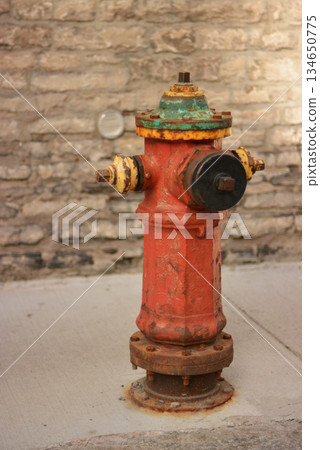 A vintage red metallic fire hydrant in the ground for fighting fires. A vintage red metallic fire hydrant in the ground for fighting fires. 134650775