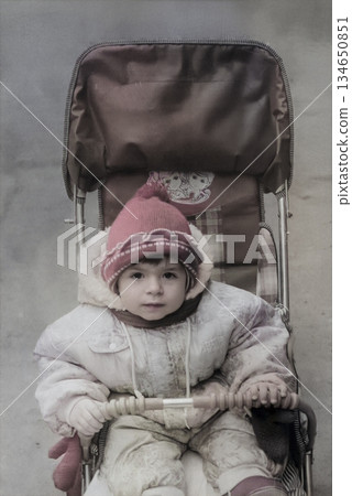A vintage portrait of a little girl taking a stroller in early spring. Retro photo from 1995. A vintage portrait of a little girl taking a stroller in early spring. Retro photo from 1995. 134650851