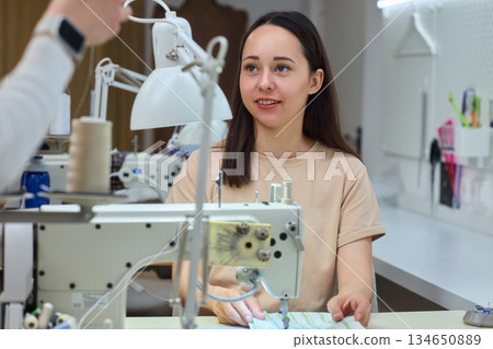A Focused Seamstress Diligently Working with a Sewing Machine in Her Creative Workspace A Focused Seamstress Diligently Working with a Sewing Machine in Her Creative Workspace 134650889