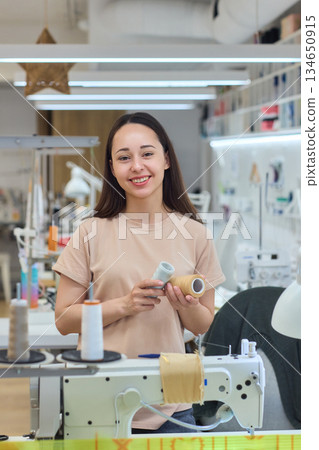 A Focused Seamstress Diligently Working with a Sewing Machine in Her Creative Workspace 134650915
