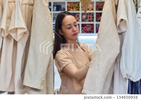 A Fashion Designer Carefully Organizing Beautiful and Elegant Dresses in Their Studio Workspace A Fashion Designer Carefully Organizing Beautiful and Elegant Dresses in Their Studio Workspace 134650938