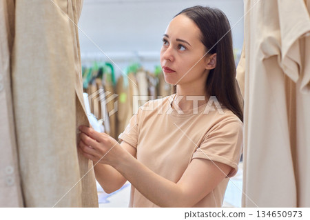 A Fashion Designer Carefully Organizing Beautiful and Elegant Dresses in Their Studio Workspace 134650973