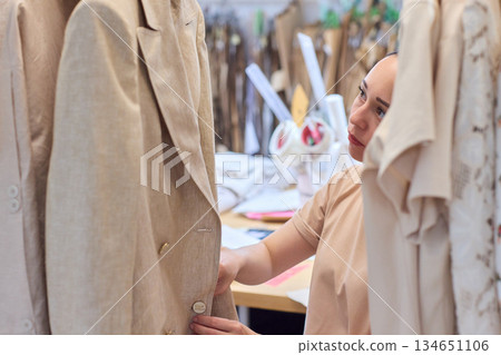 A Fashion Designer Carefully Organizing Beautiful and Elegant Dresses in Their Studio Workspace A Fashion Designer Carefully Organizing Beautiful and Elegant Dresses in Their Studio Workspace 134651106