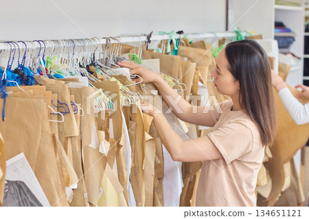 A woman is efficiently organizing the fashion media stock in her creative workspace environment 134651121