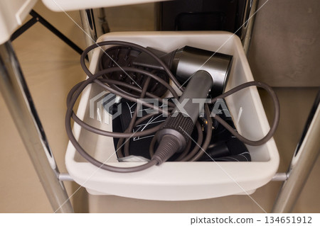 Chaotic styling station, Messy salon tools and cables, Disorganized hair dryer and equipment setup, Cluttered collection of salon devices and tangled wiring mess 134651912