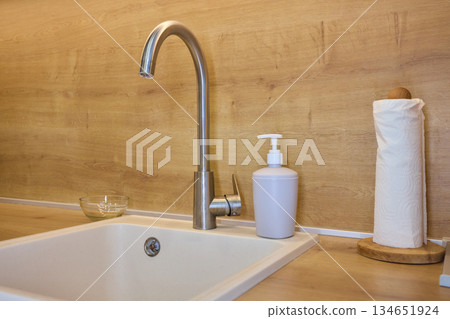 Modern clean kitchen, Sleek sink with stylish fixtures, Contemporary dining area in soft illumination, Elegant kitchen scene highlighting hygiene and ecofriendly design elements Modern clean kitchen, Sleek sink with stylish fixtures, Contemporary dining area in soft illumination, Elegant kitchen scene highlighting hygiene and ecofriendly design elements 134651924