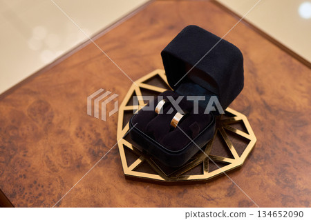 Stylish jewelry arrangement on wooden and leather textured bases, Closeup image showcasing polished gold bands displayed on sophisticated velvet and wooden surfaces Stylish jewelry arrangement on wooden and leather textured bases, Closeup image showcasing polished gold bands displayed on sophisticated velvet and wooden surfaces 134652090