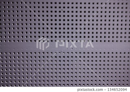 Closeup of acoustic panels showcasing geometric pattern and tactile surface, Contemporary perforated metal panels with square cutouts providing sound absorption and visual rhythm 134652094