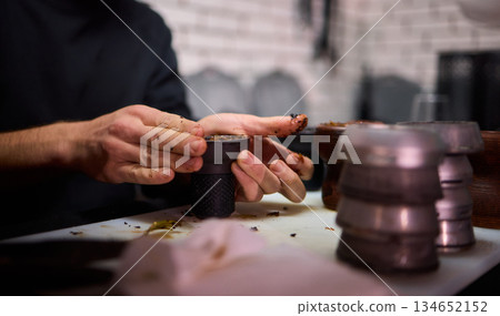 Detailed view of traditional hookah setup with tobacco and heating elements, Intimate depiction of skilled hands preparing hookah with rich tobacco and glowing coals 134652152