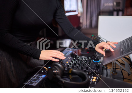 DJ setup overview, Energetic club DJ performing with digital controller in action, Content creator mixing music live using digital turntables under vibrant stage lights 134652162