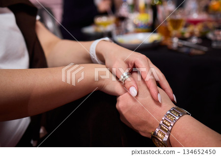 Friendly hand interlock, Close friends linked hands during joyful gathering, Intimate moment capturing friendship and reassurance with clasped hands during celebration Friendly hand interlock, Close friends linked hands during joyful gathering, Intimate moment capturing friendship and reassurance with clasped hands during celebration 134652450