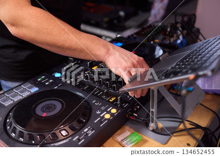 DJ setup overview, Energetic club DJ performing with digital controller in action, Content creator mixing music live using digital turntables under vibrant stage lights DJ setup overview, Energetic club DJ performing with digital controller in action, Content creator mixing music live using digital turntables under vibrant stage lights 134652455