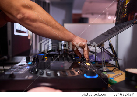 DJ setup overview, Energetic club DJ performing with digital controller in action, Content creator mixing music live using digital turntables under vibrant stage lights 134652457