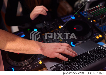 DJ setup overview, Energetic club DJ performing with digital controller in action, Content creator mixing music live using digital turntables under vibrant stage lights DJ setup overview, Energetic club DJ performing with digital controller in action, Content creator mixing music live using digital turntables under vibrant stage lights 134652460