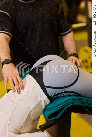Gym stretch demonstration, Closeup of gym exercise focusing on posture and mobility, Athletic instructor assists client with stretching technique emphasizing recovery and strength Gym stretch demonstration, Closeup of gym exercise focusing on posture and mobility, Athletic instructor assists client with stretching technique emphasizing recovery and strength 134652473