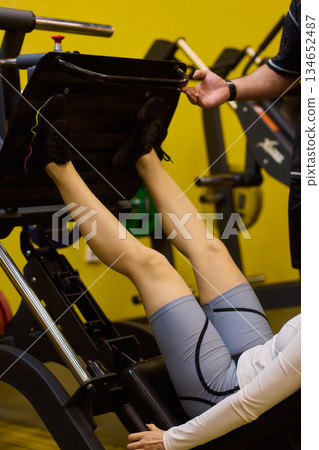 Woman exercises intensely, Intensive workout focusing on proper technique, Dynamic gym environment showing woman engaging muscles during targeted resistance training 134652487