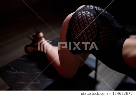 Sensual studio photograph highlighting elegant lingerie and confident posture, Artistic portrayal of provocative fashion in softly lit setting emphasizing charm and allure 134652673