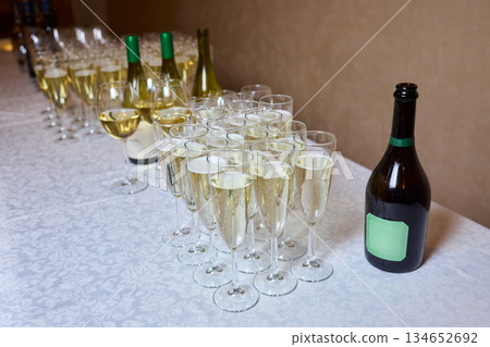 Wine glasses ready, Experience sophisticated gathering with wine and warm lighting, Refined arrangement of wine bottles and glasses perfect for socializing and celebration Wine glasses ready, Experience sophisticated gathering with wine and warm lighting, Refined arrangement of wine bottles and glasses perfect for socializing and celebration 134652692