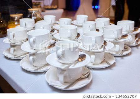 Elegant table setting, Refined display of fine china for celebration occasion, Impeccably organized porcelain teacups and saucers prepared for elegant wedding celebration Elegant table setting, Refined display of fine china for celebration occasion, Impeccably organized porcelain teacups and saucers prepared for elegant wedding celebration 134652707
