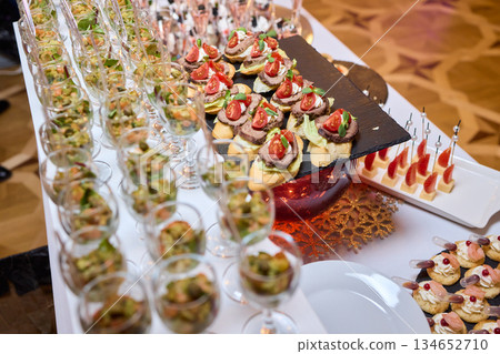 Elegant dining presentation, Sophisticated arrangement of canapes on stylish table setting, Exquisite black trays with gourmet delicacies showcased in upscale event ambiance Elegant dining presentation, Sophisticated arrangement of canapes on stylish table setting, Exquisite black trays with gourmet delicacies showcased in upscale event ambiance 134652710