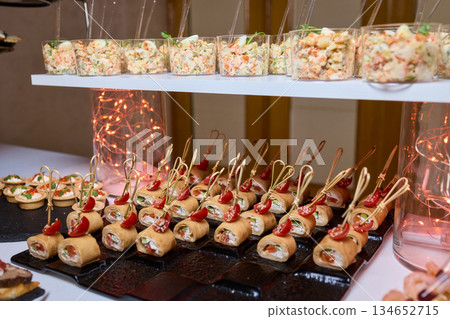 Elegant dining presentation, Sophisticated arrangement of canapes on stylish table setting, Exquisite black trays with gourmet delicacies showcased in upscale event ambiance Elegant dining presentation, Sophisticated arrangement of canapes on stylish table setting, Exquisite black trays with gourmet delicacies showcased in upscale event ambiance 134652715