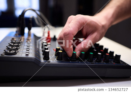 Tactile fingers manipulate illuminated dials during soundcheck setup, Professional technician finetunes sound equipment with multiple cables connected under moody studio lighting Tactile fingers manipulate illuminated dials during soundcheck setup, Professional technician finetunes sound equipment with multiple cables connected under moody studio lighting 134652727
