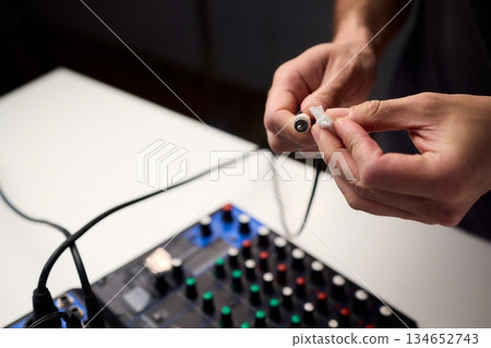 Personnel meticulously maintain audio equipment hygiene, Detailed shot of technician carefully cleaning audio cable with soft cloth in professional studio environment Personnel meticulously maintain audio equipment hygiene, Detailed shot of technician carefully cleaning audio cable with soft cloth in professional studio environment 134652743