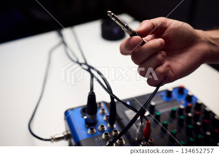 Audio setup preparation, Closeup images of connections during soundcheck setup process, Scene capturing stabilizing cables and adjusting controls before recording begins 134652757