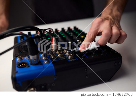 Closeup of audio control panel, Technician finetunes mixer controls and inspects connections, Focused technician performing maintenance on audio mixer controls and LEDs Closeup of audio control panel, Technician finetunes mixer controls and inspects connections, Focused technician performing maintenance on audio mixer controls and LEDs 134652763