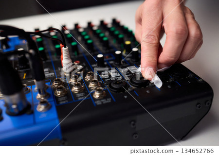 Closeup of audio control panel, Technician finetunes mixer controls and inspects connections, Focused technician performing maintenance on audio mixer controls and LEDs 134652766