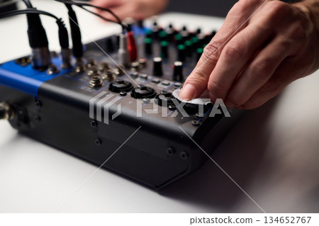 Closeup of audio control panel, Technician finetunes mixer controls and inspects connections, Focused technician performing maintenance on audio mixer controls and LEDs 134652767