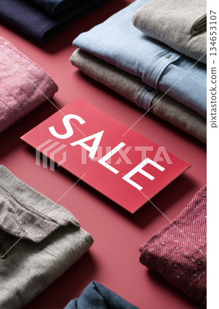 Overhead View of Folded Clothes and Red SALE Sign in Modern Retail Flat Lay 134653107
